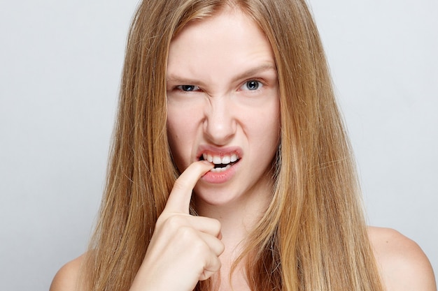 Retrato de uma jovem bonita nervosa roendo as unhas