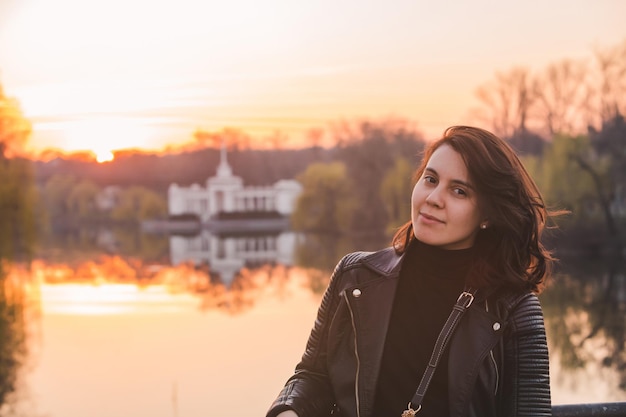 Retrato de uma jovem bonita no rio pôr do sol no fundo