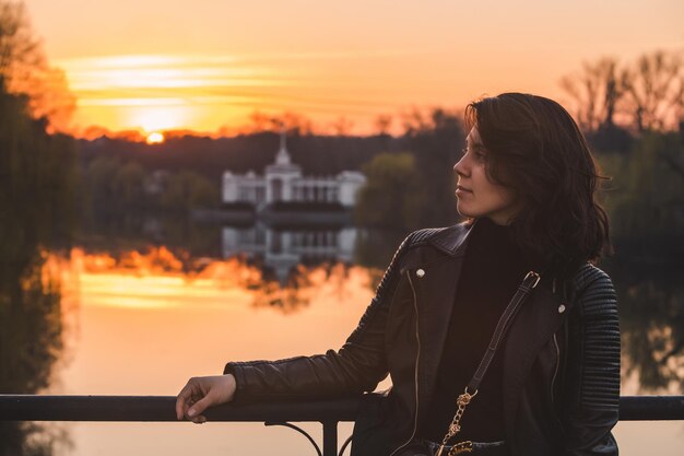 Retrato de uma jovem bonita no rio pôr do sol no fundo