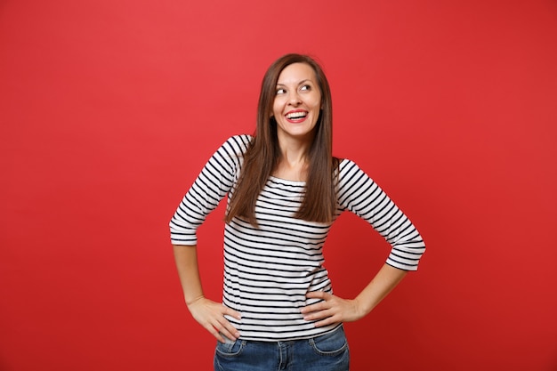 Retrato de uma jovem bonita sonhadora com roupas listradas, olhando para cima, com as mãos na cintura