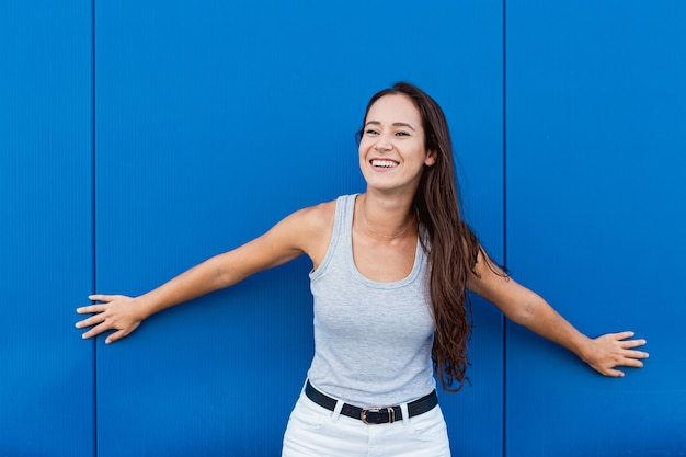 Retrato de uma jovem bonita sorrindo e posando com uma parede azul ao fundo