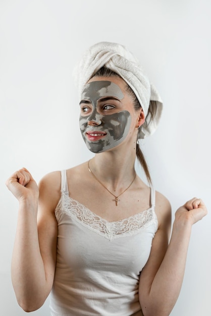 Retrato de uma jovem bonita usando uma máscara de barro preto de beleza no rosto isolado em branco