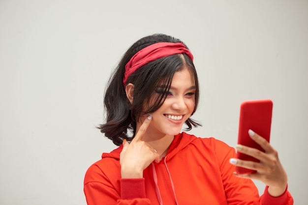 Retrato de uma jovem brincalhona segurando um telefone celular sobre fundo branco