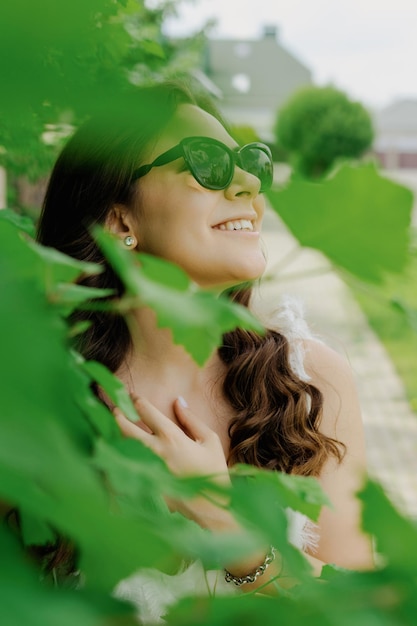 Retrato de uma jovem caminhando em um dia de verão Uma bela modelo em um vestido branco e óculos de sol posa do lado de fora