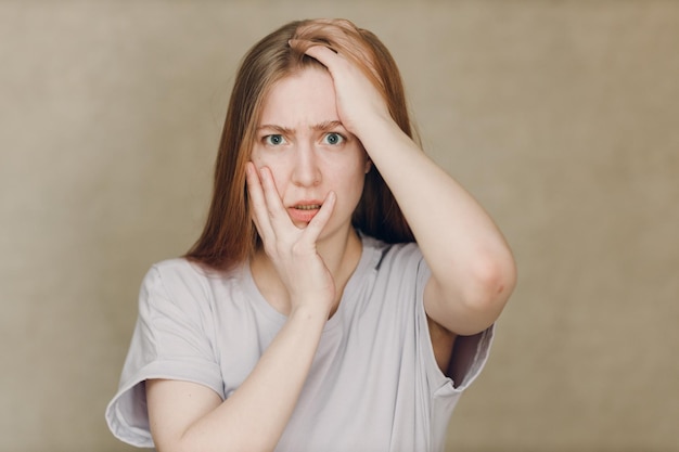 Retrato de uma jovem caucasiana chateada olhando para a câmera contra um fundo bege