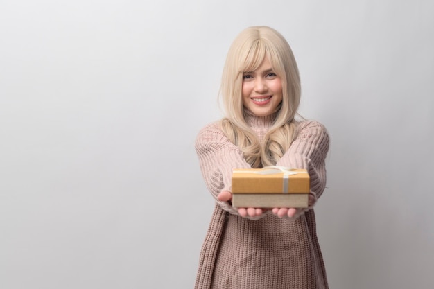 Retrato de uma jovem caucasiana vestindo suéter segurando caixa de presentes sobre fundo branco