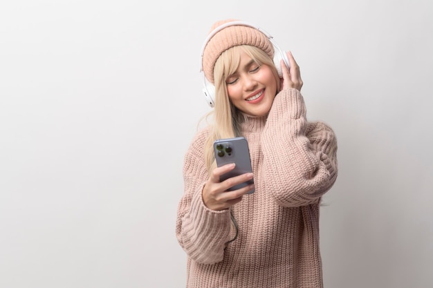 Retrato de uma jovem caucasiana vestindo suéter segurando telefone inteligente sobre fundo branco