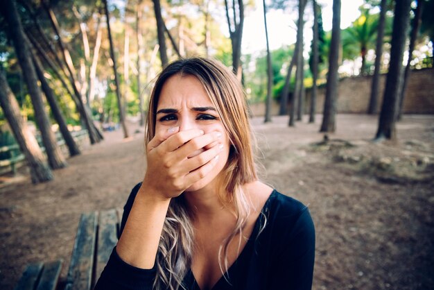 Foto retrato de uma jovem cobrindo a boca na floresta