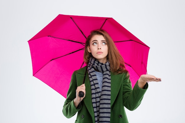 Retrato de uma jovem com casaco e lenço segurando guarda-chuva isolado em um fundo branco