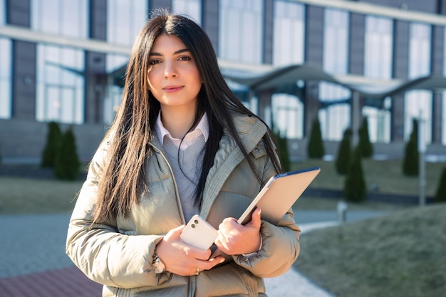 Retrato de uma jovem com laptops no fundo de um prédio de escritórios