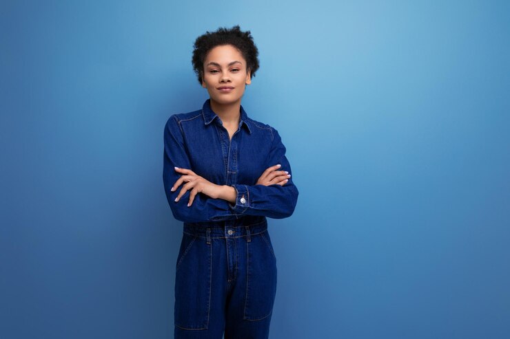 Retrato de uma jovem com pele escura e cabelo preto encaracolado vestido com macacão jeans azul