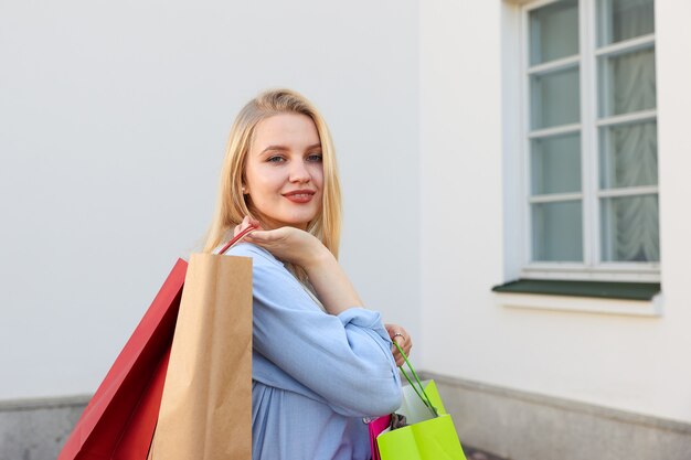 Retrato de uma jovem com sacolas coloridas depois de fazer compras