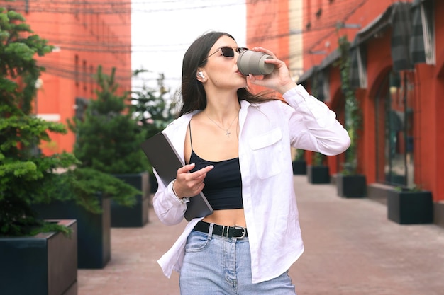 Retrato de uma jovem com um laptop e uma xícara de café que vai ao escritório