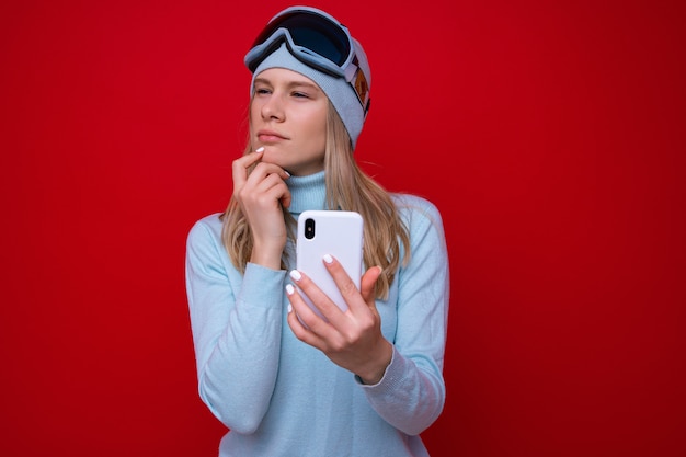 Retrato de uma jovem com um suéter e óculos de esqui com um telefone