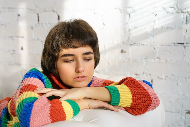 Foto retrato de uma jovem com uma camisola multicolor, triste