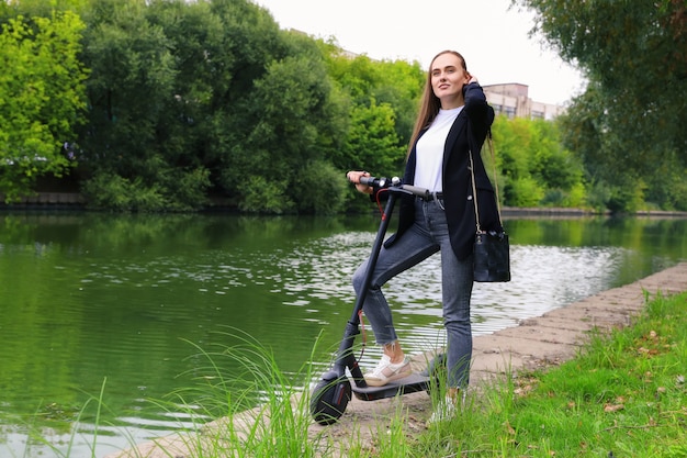 Retrato de uma jovem com uma scooter elétrica no parque