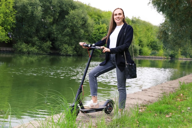 Retrato de uma jovem com uma scooter elétrica no parque