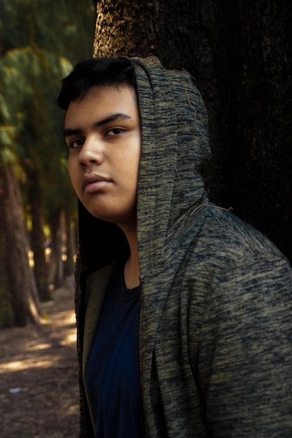 Foto retrato de uma jovem contra o tronco de uma árvore na floresta