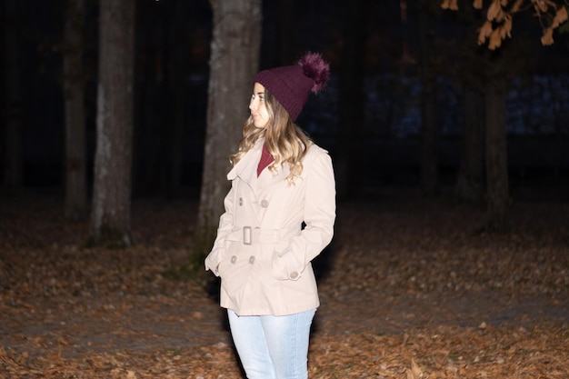 Retrato de uma jovem de gorro e casaco de lã à noite no parque no outono