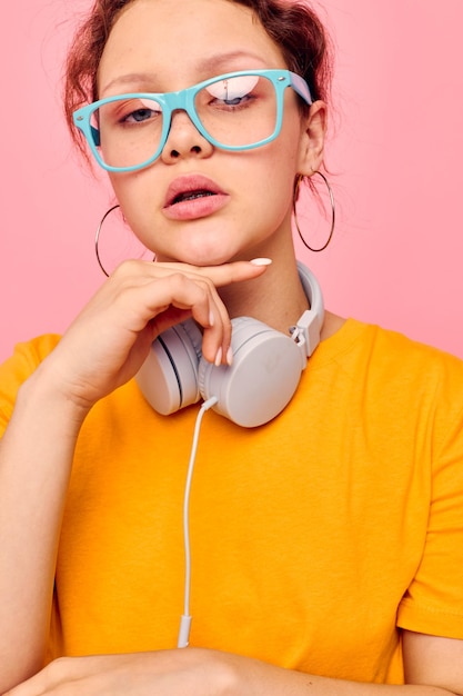 Retrato de uma jovem de óculos azuis ouvindo música em fones de ouvido vista cortada inalterada