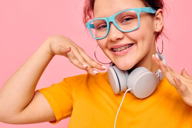 Retrato de uma jovem de óculos azuis ouvindo música em fones de ouvido vista cortada inalterada