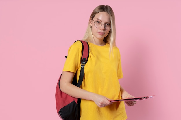 Foto retrato de uma jovem de óculos e segurando sua pasta e sua mochila