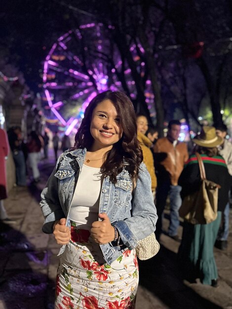 Foto retrato de uma jovem de pé contra a cidade iluminada à noite