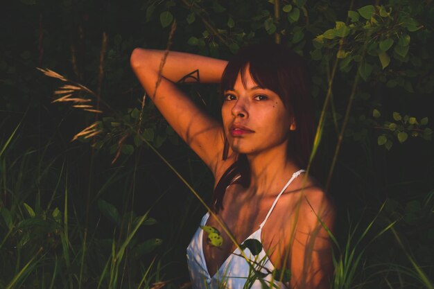 Foto retrato de uma jovem de pé contra plantas