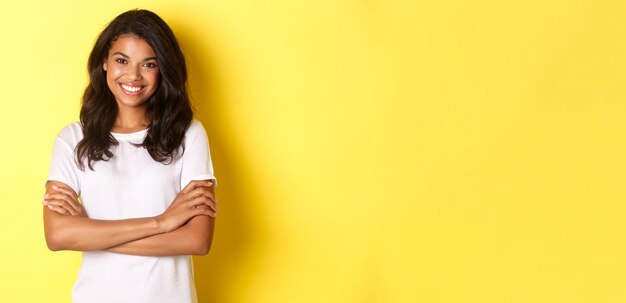 Foto retrato de uma jovem de pé contra um fundo amarelo