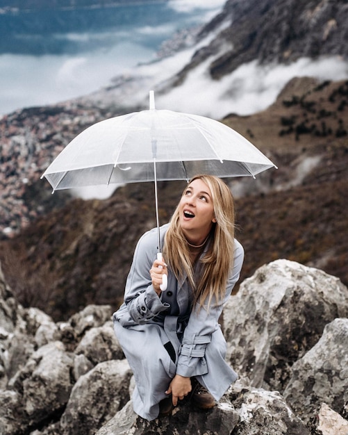 Retrato de uma jovem de pé em uma rocha com um guarda-chuva