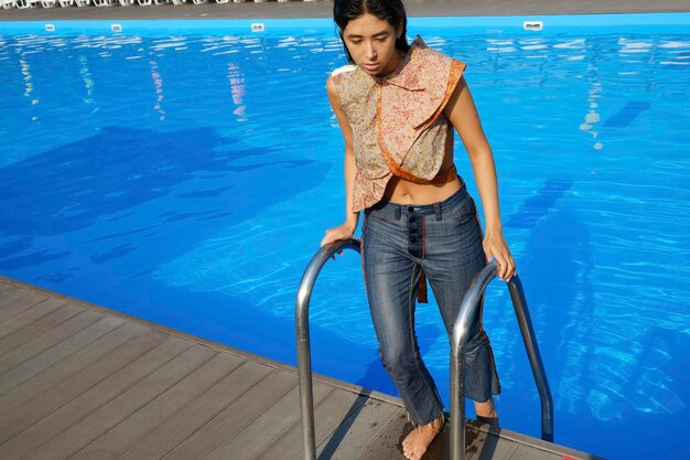 Foto retrato de uma jovem de pé na piscina