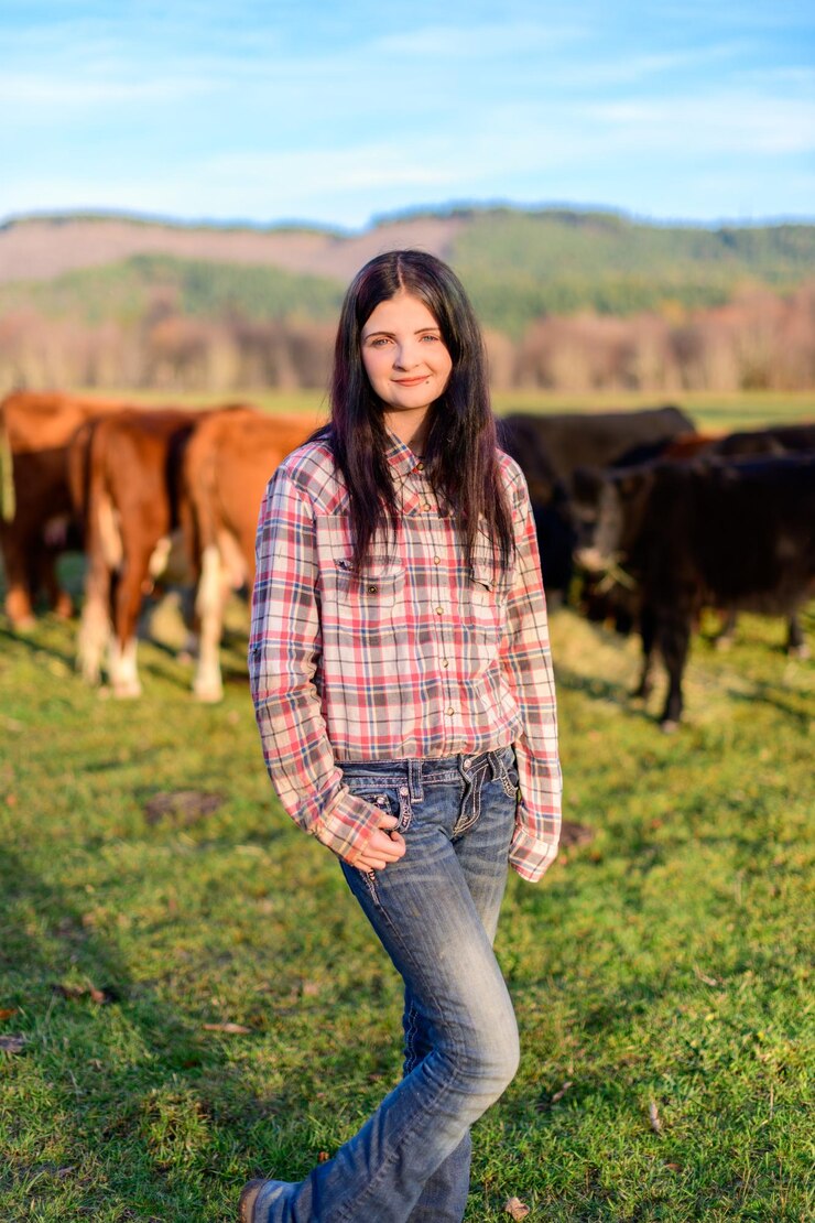 Foto retrato de uma jovem de pé no campo com o gado