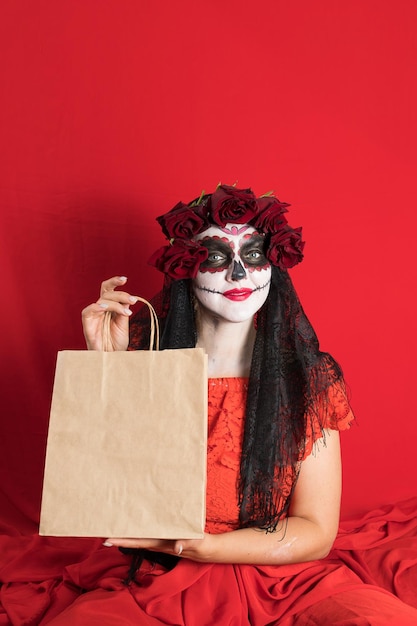 Retrato de uma jovem de vestido vermelho e maquiagem tradicional de caveira de açúcar para a celebração do Dia de los Muertos o Dia dos Mortos