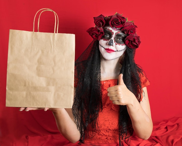 Retrato de uma jovem de vestido vermelho e maquiagem tradicional de caveira de açúcar para a celebração do Dia de los Muertos o Dia dos Mortos