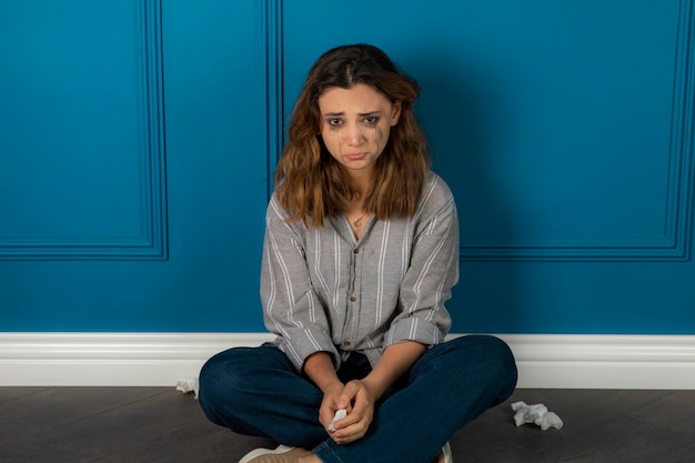 Retrato de uma jovem deprimida sentada no chão e chorando. Foto de alta qualidade