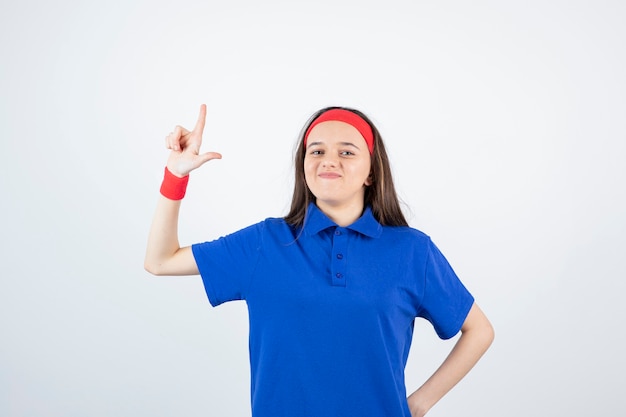 Retrato de uma jovem desportiva em pé e apontando para cima