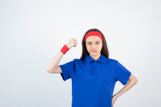 Retrato de uma jovem desportiva em pé e mostrando os bíceps