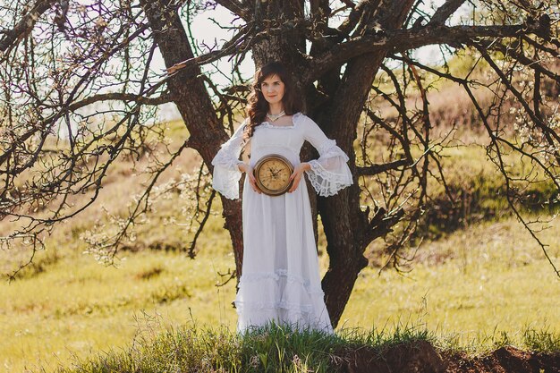 Retrato de uma jovem despreocupada em um vestido branco estilo casamento vintage no vale do jardim da primavera