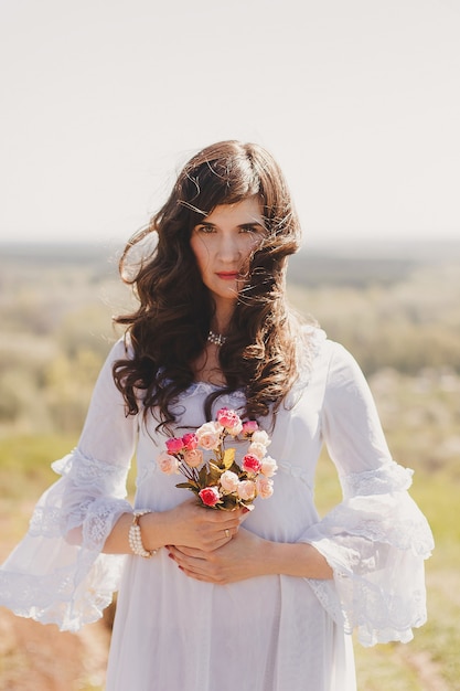 Retrato de uma jovem despreocupada em um vestido branco estilo casamento vintage no vale do jardim da primavera