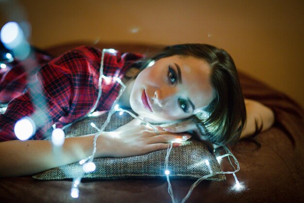 Retrato de uma jovem e atraente garota bósnia com luzes bokeh de Natal