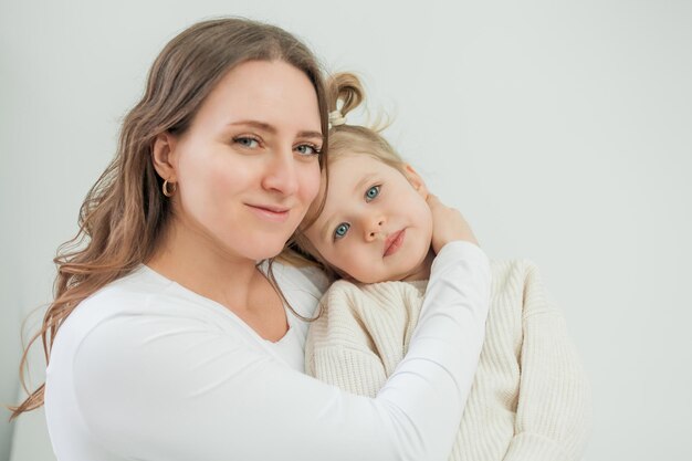 Foto retrato de uma jovem e bela mãe com uma filha de 3 anos de idade em fundo branco maternidade