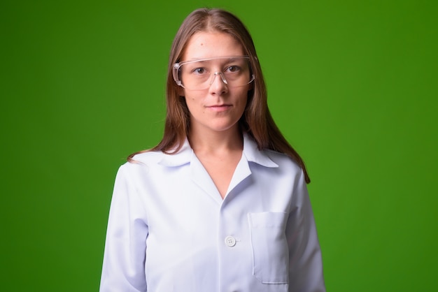 Retrato de uma jovem e bela médica contra uma parede verde