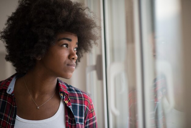 retrato de uma jovem e bela mulher afro-americana com cabelos cacheados perto da janela