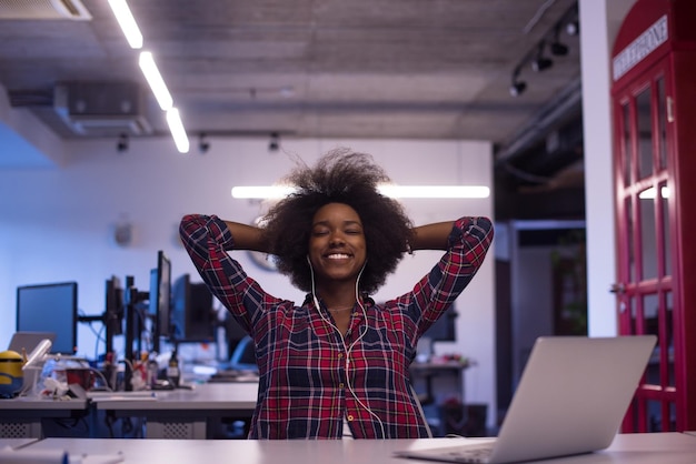 retrato de uma jovem e bela mulher afro-americana de sucesso que gosta de passar um tempo alegre e de qualidade enquanto trabalha em um grande escritório moderno