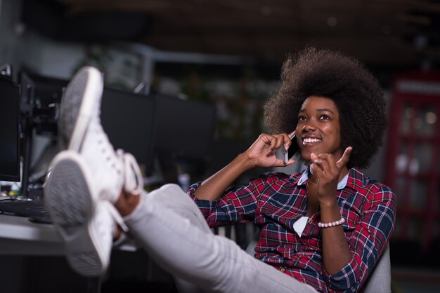 retrato de uma jovem e bela mulher afro-americana de sucesso que gosta de passar um tempo alegre e de qualidade enquanto trabalha em um grande escritório moderno