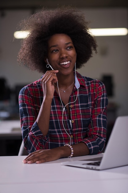 Foto retrato de uma jovem e bela mulher afro-americana de sucesso que gosta de passar um tempo alegre e de qualidade enquanto trabalha em um grande escritório moderno