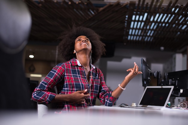 retrato de uma jovem e bela mulher afro-americana de sucesso que gosta de passar um tempo alegre e de qualidade enquanto trabalha em um grande escritório moderno