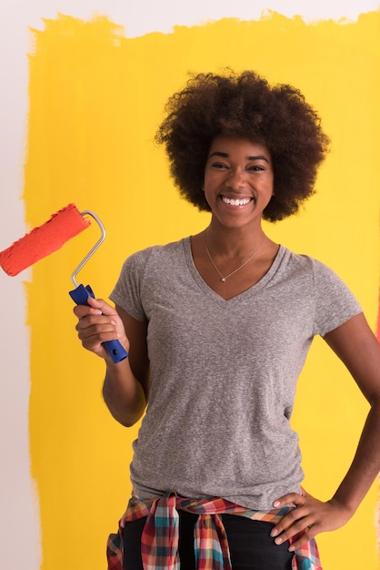 retrato de uma jovem e bela mulher afro-americana pintando a parede em seu novo apartamento