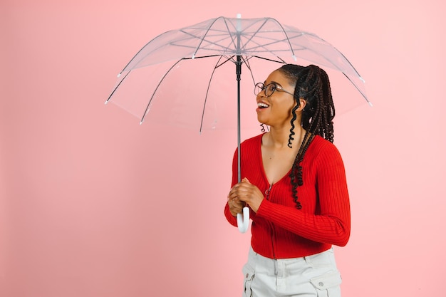 Retrato de uma jovem e bela mulher afro-americana segurando guarda-chuva isolado em um fundo rosa