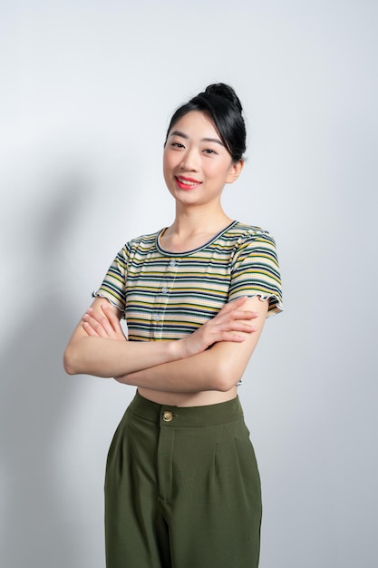 Retrato de uma jovem e bela mulher asiática de pé e sorrindo isolada em fundo branco olhando para a câmera